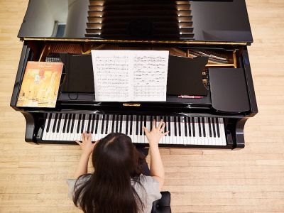 Student sat at a piano. Photograph taken from above their head looking down.
